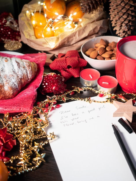 Weihnachtsdekoration mit begonnenem Brief an den Weihnachtsmann auf dem Tisch