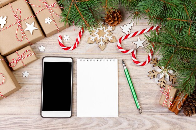 Weihnachtsdekoration mit Geschenkboxen, Handy und leerem Notizbuch