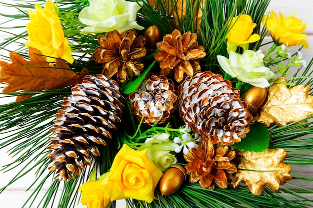 Weihnachtsdekoration mit goldenen verzierten Tannenzapfen und Seidenrosen