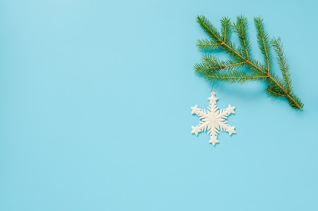 Weihnachtsdekoration Schneeflockenspielzeug auf Tannenzweig auf blauem Hintergrund. Konzept Frohe Weihnachten oder ein gutes neues Jahr.