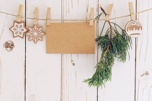 Weihnachtsdekoration und leere Papierkarte hängen auf Holzhintergrund.