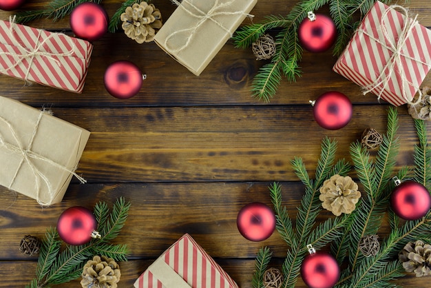 Weihnachtsdekorationen, Geschenkbox, Kiefernkegel und rote Bälle auf einem braunen Holztisch