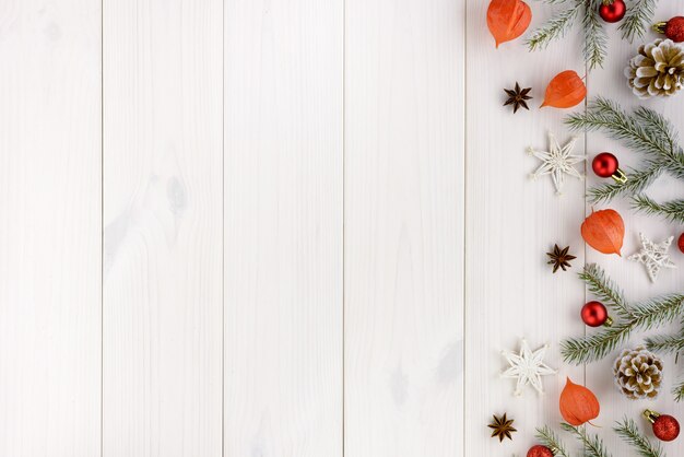 Weihnachtsdekorationen, Kiefernkegel, Sterne und rote Bälle auf einem weißen Holztisch.