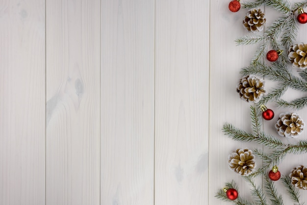 Weihnachtsdekorationen, Tannenzapfen und rote Bälle auf einem weißen Holztisch. Draufsicht, Kopie, Raum.