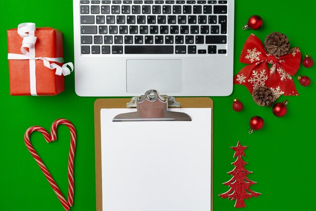 Weihnachtsdekorationen und Computer-Laptop auf Papierhintergrund-Draufsicht