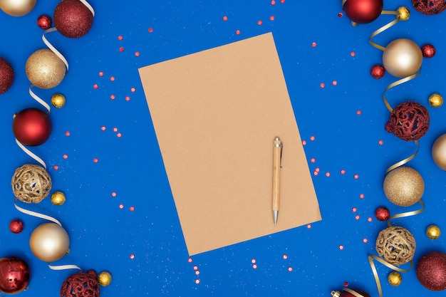 Weihnachtsdekorationen und leeres Bastelblatt Papier und Stift auf blauem Papierhintergrund.