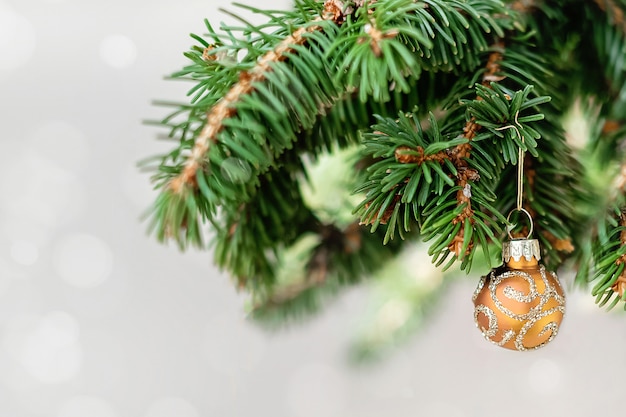 Weihnachtsdekorationsrand aus Fichtenzweigen, Tannenzapfen und rot glänzenden Kugeln auf luftigem Bokeh-Licht