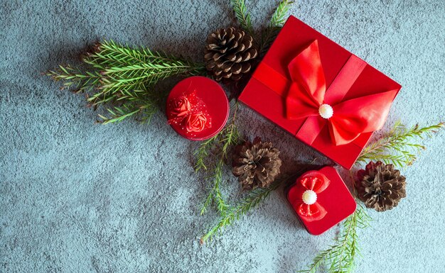 Weihnachtsdekorationszusammensetzung auf grauem konkretem Hintergrund mit einer schönen roten Geschenkbox