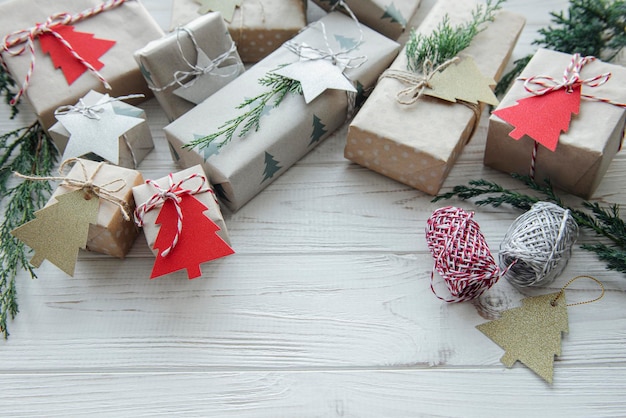 Weihnachtsdekorative hausgemachte Geschenkboxen in braunem Kraftpapier auf einem weißen Holztisch