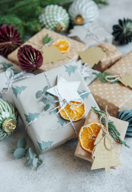 Weihnachtsdekorative hausgemachte geschenkboxen in braunem kraftpapier auf grauem betonhintergrund