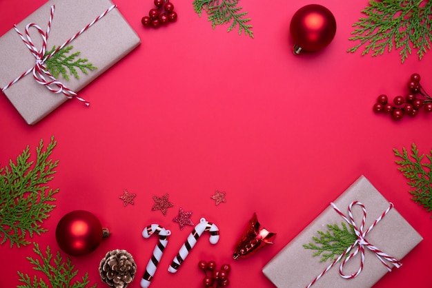 Weihnachtsdraufsicht der Geschenkbox mit Fichtenzweigen, Kiefernkegeln, roten Beeren auf rotem backgr