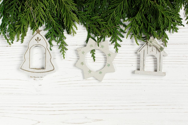 Foto weihnachtseinfache spielwaren auf grünen ästen auf stilvollem weißem rustikalem hölzernem hintergrundraum für feiertagsgrußkartenkonzept ungewöhnliche kreative draufsicht