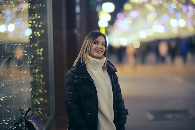 Weihnachtseinkaufsmädchenstadt, junges vorbildliches abendliches Geschenkeeinkaufen, saisonaler Verkauf, Winterabend draußen in der Stadt