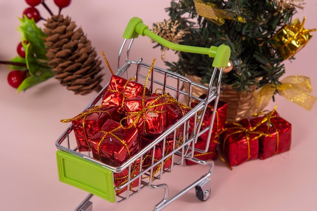 Weihnachtseinkaufswagen mit Geschenken und Weihnachtsbaum im Hintergrund