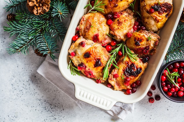 Weihnachtsessen, gebackenes hühnerfleisch mit preiselbeeren und rosmarin in der auflaufform, weiße fläche, textfreiraum,