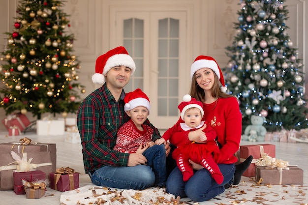 Weihnachtsfamilie! Glückliche Mutter, Vater und kleine Tochter und Sohn auf Weihnachtsmannmütze