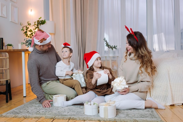 Weihnachtsfamilie Glückliches Porträt, Vater, Mutter und Tochter in Sankt-Hüten sitzend