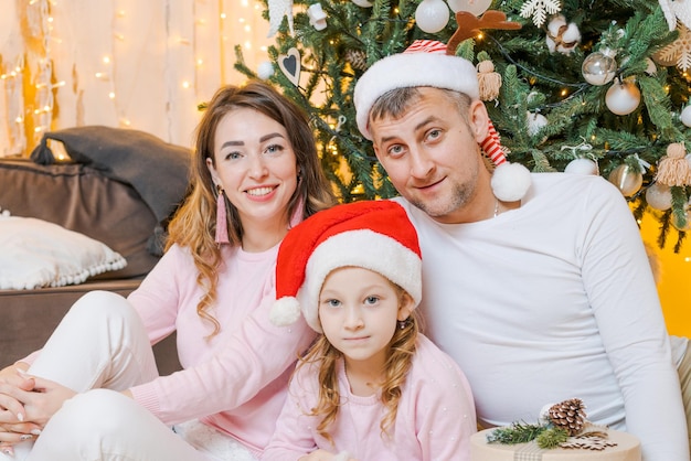 Weihnachtsfamilie Glückliches Porträt, Vater, Mutter und Tochter in Sankt-Hüten sitzend