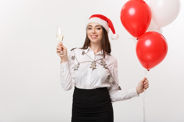 Weihnachtsfeier - Junge schöne Geschäftsfrau, die Weihnachten mit Glas Champagner und Konfetti Wand feiert.