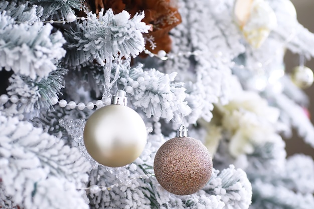 Weihnachtsfeiertag-Hintergrund. Silber- und Farbflitter, der von einem verzierten Baum mit Bokeh und Schnee hängt, Kopienraum.