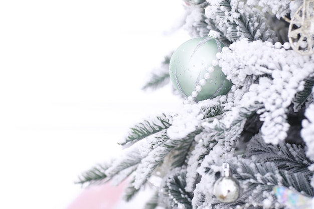 Weihnachtsfeiertagshintergrund silber- und farbkugel, die an einem geschmückten baum mit bokeh- und schneekopierraum hängt