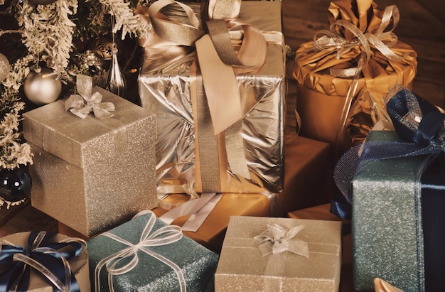 Weihnachtsfeiertagshintergrund von Kästen mit Geschenken des neuen Jahres unter verziertem Weihnachtsbaum im Wohnzimmer Close-up-Geschenke Verpackt mit Bändern, Dekor unter Baum im Innenbereich. Platz für Website kopieren