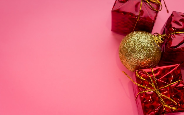 Weihnachtsfeiertagszene - Goldglänzender Flitter, rote Geschenkboxen auf rosa Hintergrund mit copyspace