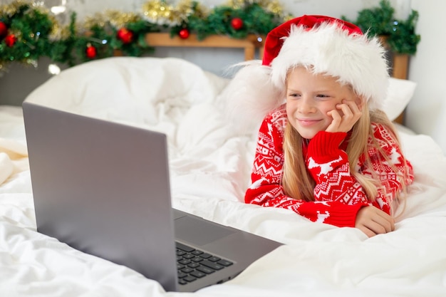 Weihnachtsfernunterricht Online-Bildung Schulmädchen lernt zu Hause mit digitalem Tablet-Laptop-Notebook auf dem Bett und macht Schulhausaufgaben