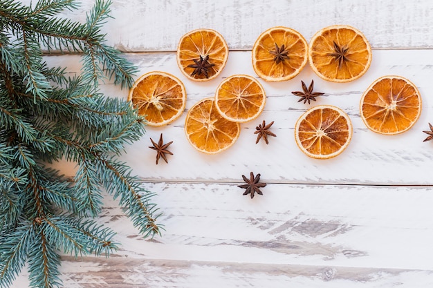 Weihnachtsfestivw-Hintergrund mit Tannenzweigen, getrockneten Orangen und Anissternen auf rustikalem Holztisch. Draufsicht mit Kopienraum