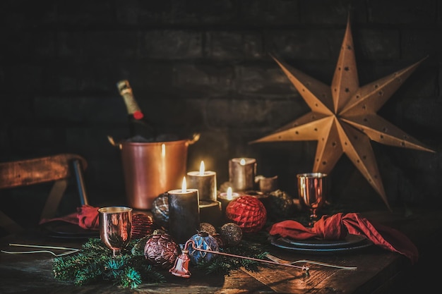 Weihnachtsfestliche Tischdekoration mit Champagnerkerzen, Dekorationen und Ästen