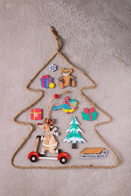 Weihnachtsfiguren aus Holz sind mit bunten Farben bemalt und in einem Weihnachtsbaum aus grobem Seil ausgelegt