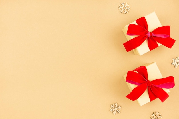 Weihnachtsflache Lage mit Geschenkboxen mit rotem Band und Schneeflockendekoration auf Bastelpapierhintergrund Festlich gestaltete Mockup-Komposition Draufsicht Kopierbereich