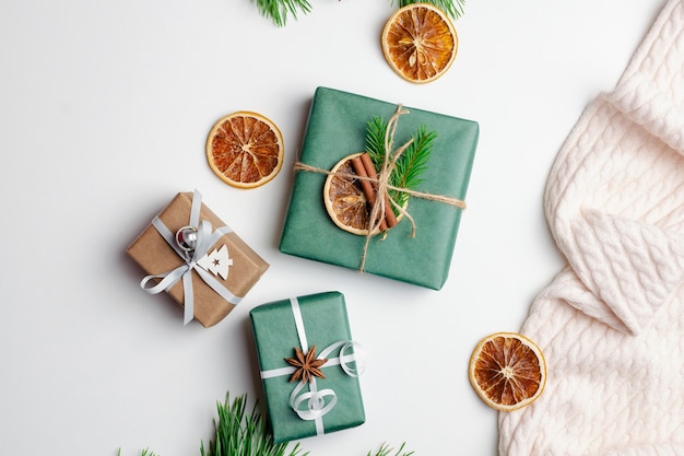 Weihnachtsflache mit dekorierten Geschenkboxen und trockenen Orangen auf Weiß