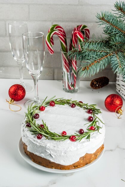 Weihnachtsfruchtkuchen oder -pudding, verziert mit Rosmarin und Moosbeere, mit Weihnachtsdekoration, auf weißer Marmortabelle, Kopienraum