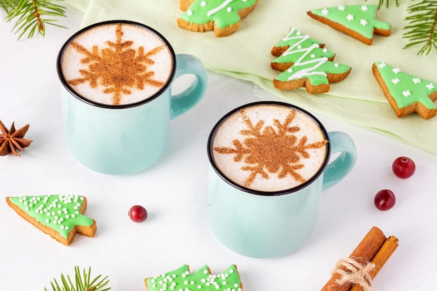 Weihnachtsfrühstück mit tannenbaumförmigen Keksen und Latte mit Zimtschneeflocken auf weißem Hintergrund.