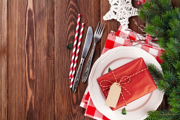 Weihnachtsgedeck mit Geschenkbox und Tannenbaum auf Holztisch. Draufsicht mit Kopienraum