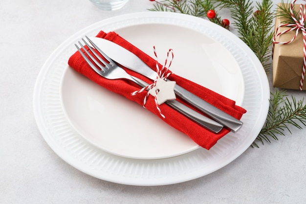 Weihnachtsgedeck mit Tellern, roter Serviette, Gabel und Messer