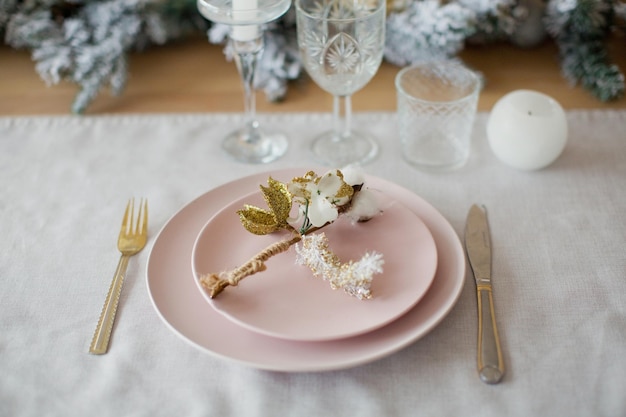 Weihnachtsgedeck Winterurlaub serviert Rosa Teller mit goldenen Blumen auf einem Holztisch mit Servietten Kerzen und Weihnachtsschmuck