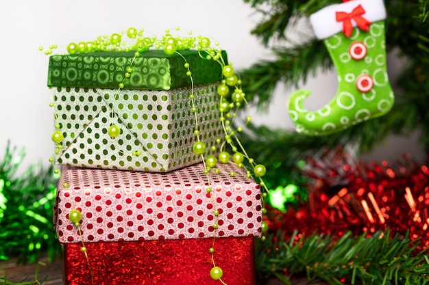 Weihnachtsgeist. Ein Paar Geschenke verpackt in einer hellen festlichen Verpackung, neben der sich ein heller Lutscher in Form eines Zuckerrohrs befindet, auf einem Holztisch neben dem Weihnachtsbaum. Nahansicht.