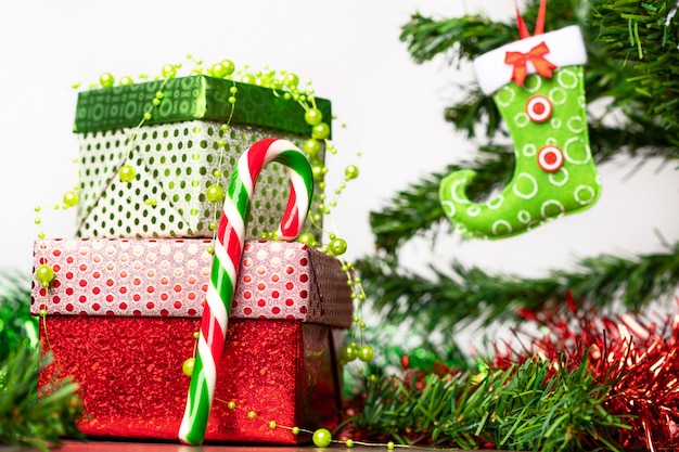 Weihnachtsgeist. Ein Paar Geschenke verpackt in einer hellen festlichen Verpackung, neben der sich ein heller Lutscher in Form eines Zuckerrohrs befindet, auf einem Holztisch neben dem Weihnachtsbaum.