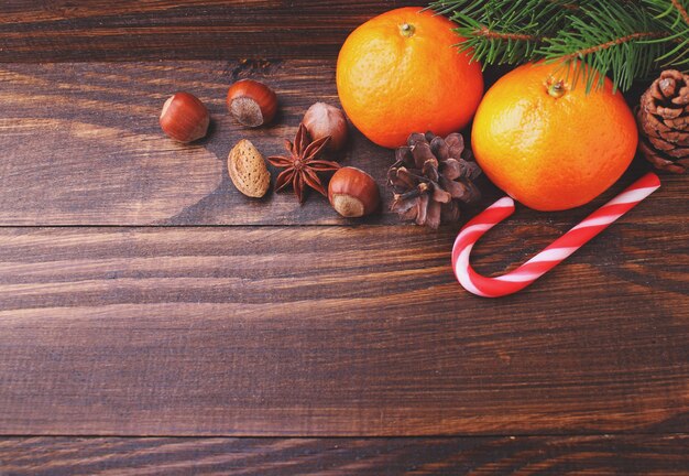 Weihnachtsgeist: Nüsse, Mandarinen, Weihnachtsbaum auf einem dunklen hölzernen Hintergrund