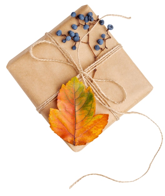 Weihnachtsgeschenk. Herbstliche Naturblätter und Kraftpapier als Dekoration.