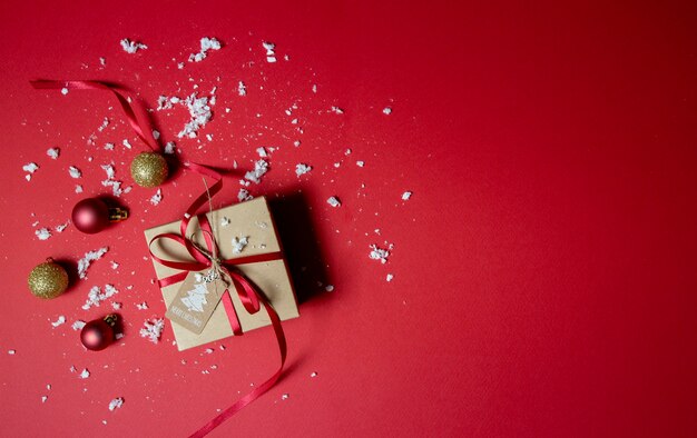 Weihnachtsgeschenk mit Kugeln auf rotem Hintergrund