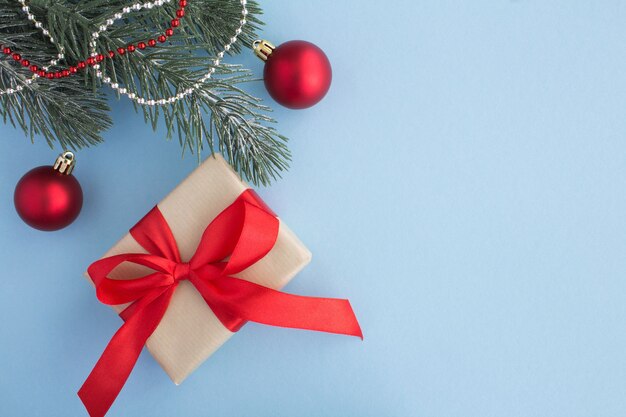 Weihnachtsgeschenk mit rotem Band und Weihnachtszusammensetzung auf dem blauen Hintergrund. Draufsicht. Speicherplatz kopieren.