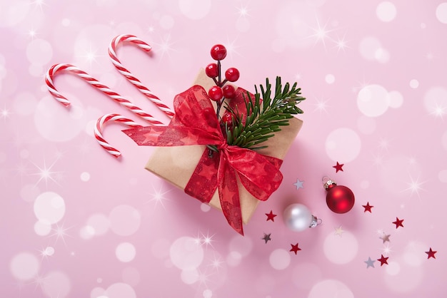 Weihnachtsgeschenkbox dekoriert Red Bow Candy Cane Fichtenzweige und Holly Beeren auf rosa Hintergrund