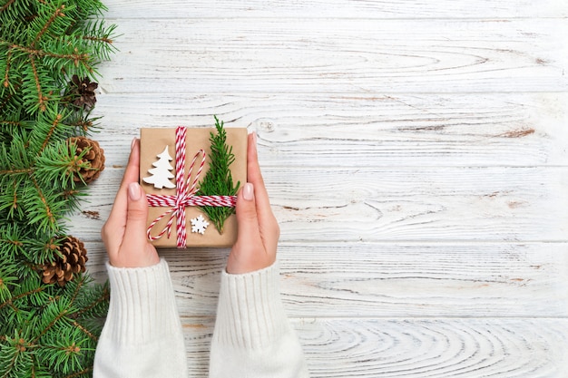 Weihnachtsgeschenkbox eingewickelt im Recyclingpapier, mit Bandbogen, mit Band auf rustikalem. Urlaub