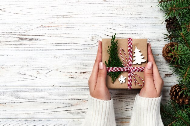 Weihnachtsgeschenkbox eingewickelt im Recyclingpapier, mit Bandbogen, mit Band auf rustikaler Weinlesetabelle. Ferienkonzept