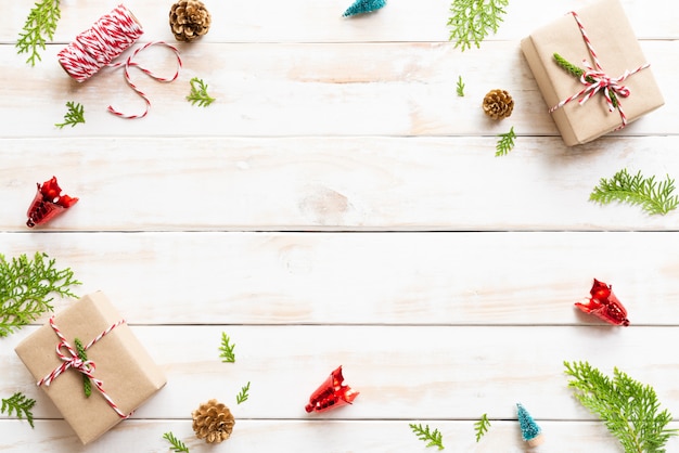 Weihnachtsgeschenkbox, Kiefernkegel, roter Stern und Glocke auf einem hölzernen Hintergrund.