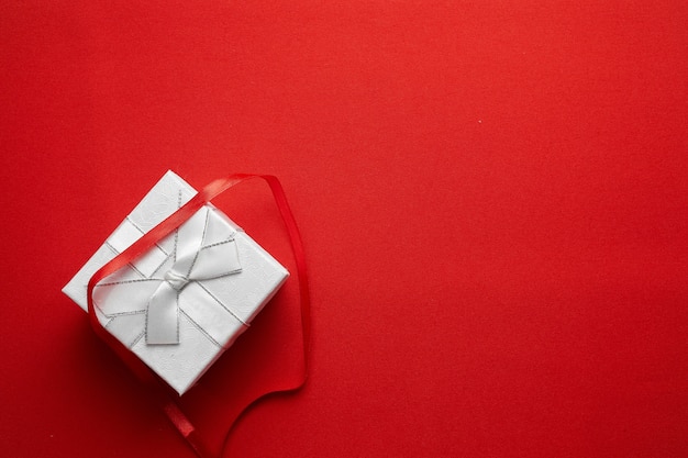 Weihnachtsgeschenkbox mit rotem Band auf rotem Grund