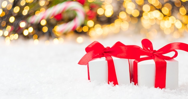 Weihnachtsgeschenkbox mit rotem Band und Bogen auf dem Schnee